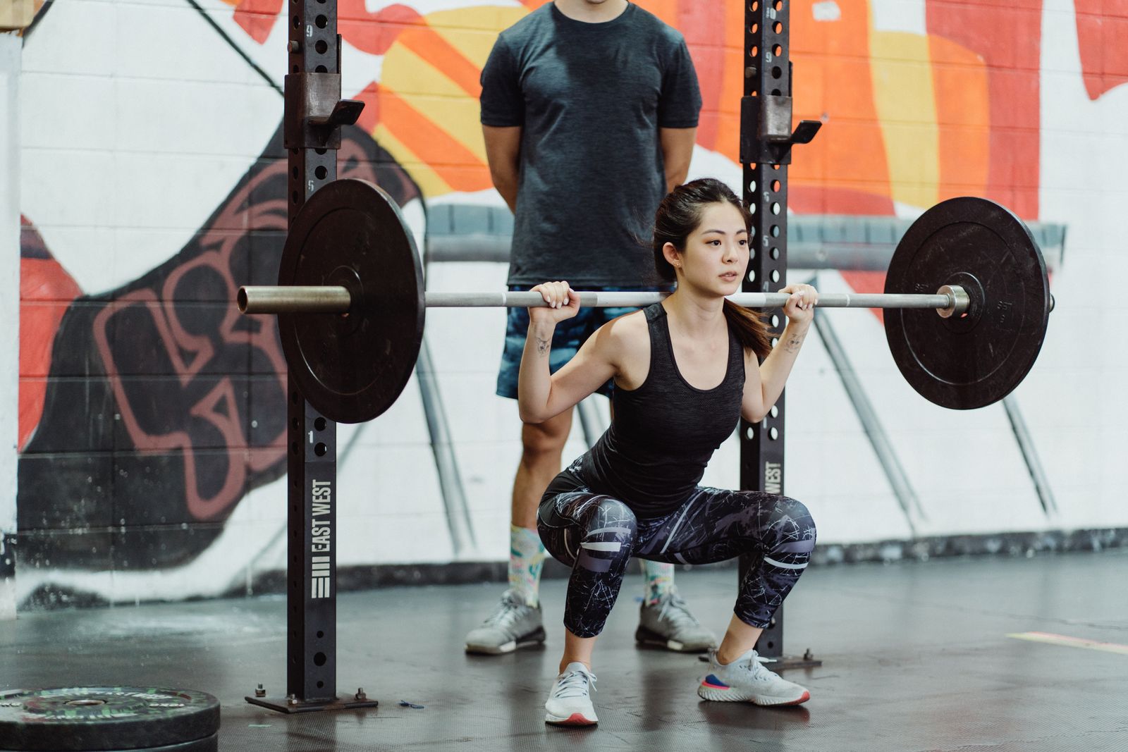 A fitness trainer assists a man in performing push-ups with equipment in a gym setting.