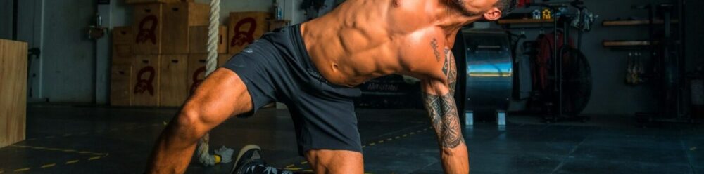 man in black shorts and black tank top doing push up