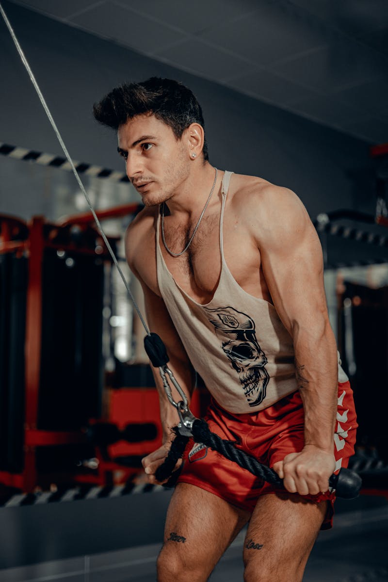 Athletic man performing cable machine tricep workout in a modern gym.