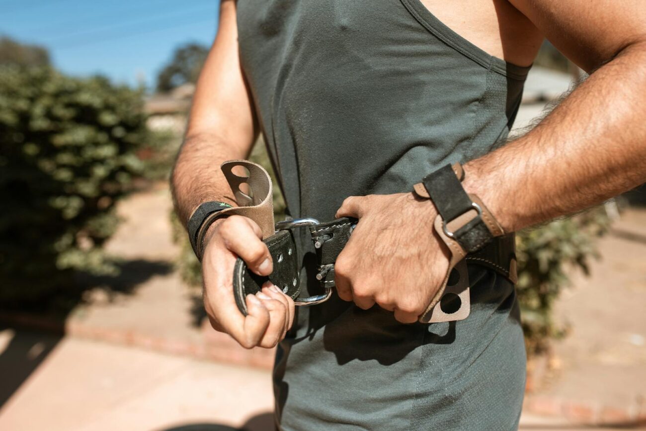 Close-up of male athlete adjusting a leather belt during an outdoor workout.