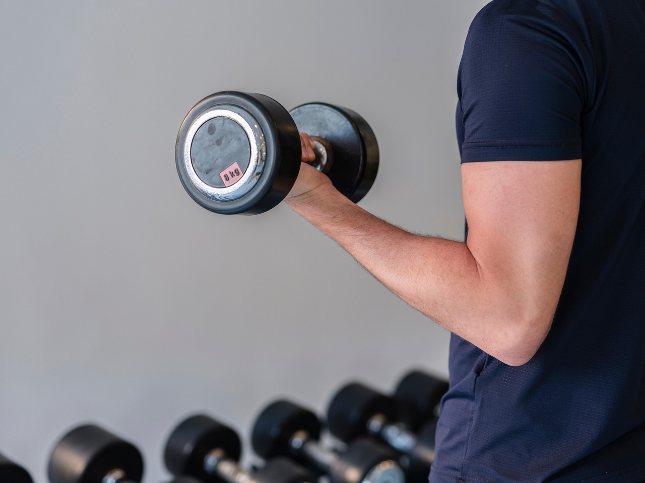 A close-up of a man performing a controlled dumbbell curl, showing the focused effort that drives muscle growth