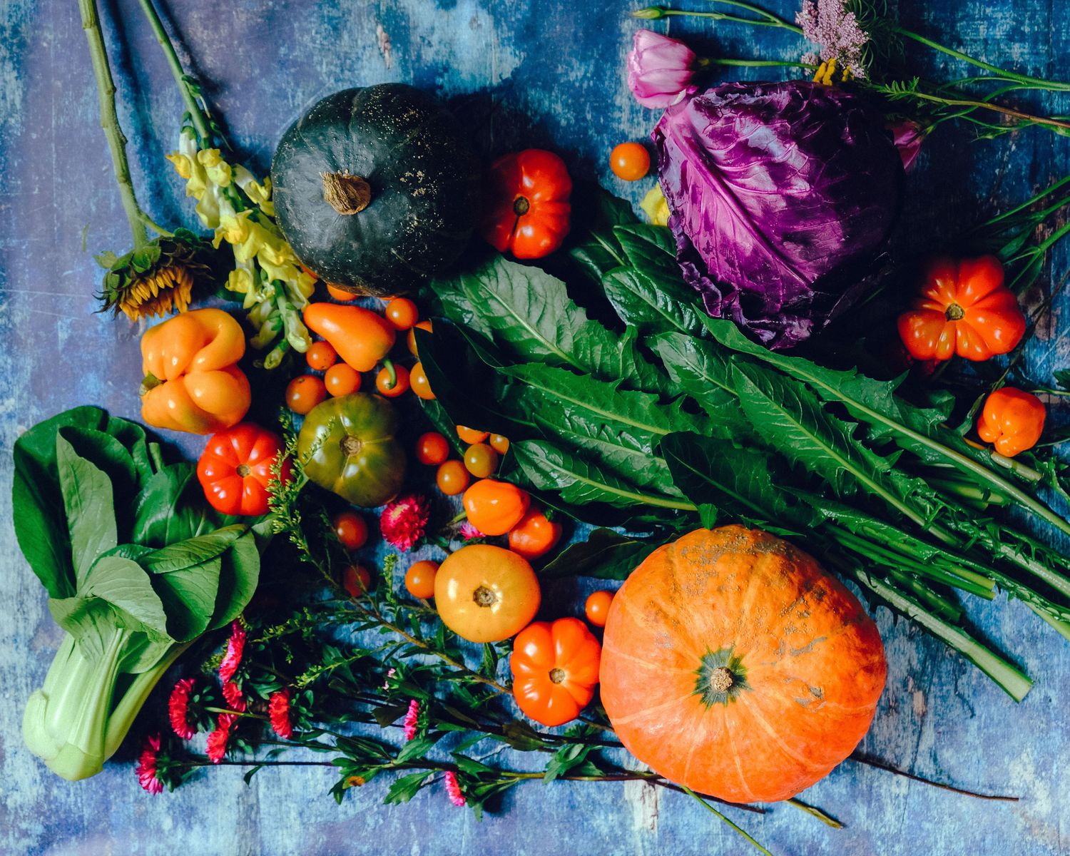 A colorful spread of fresh vegetables including cabbage, peppers, tomatoes, and leafy greens, which fill you up for fewer calories