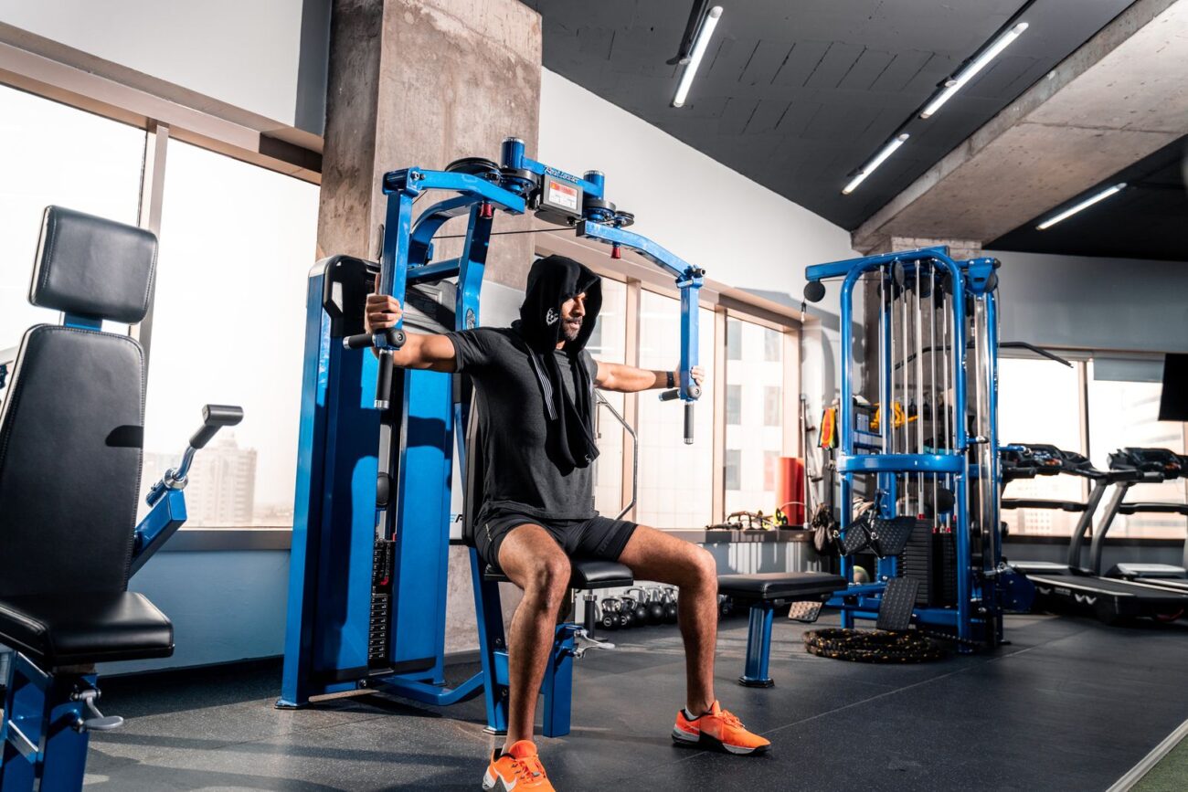 A person using a cable resistance machine in a gym, illustrating proper use of gym equipment