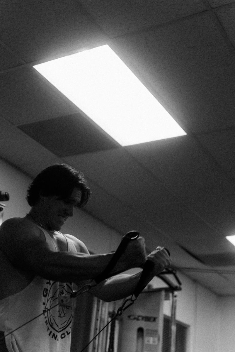 A lifter training on a cable machine in a gym, building strength through foundational training