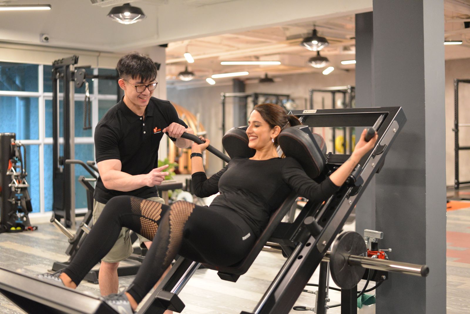 A person using a hack squat machine with a trainer, one of several alternatives to the barbell squat