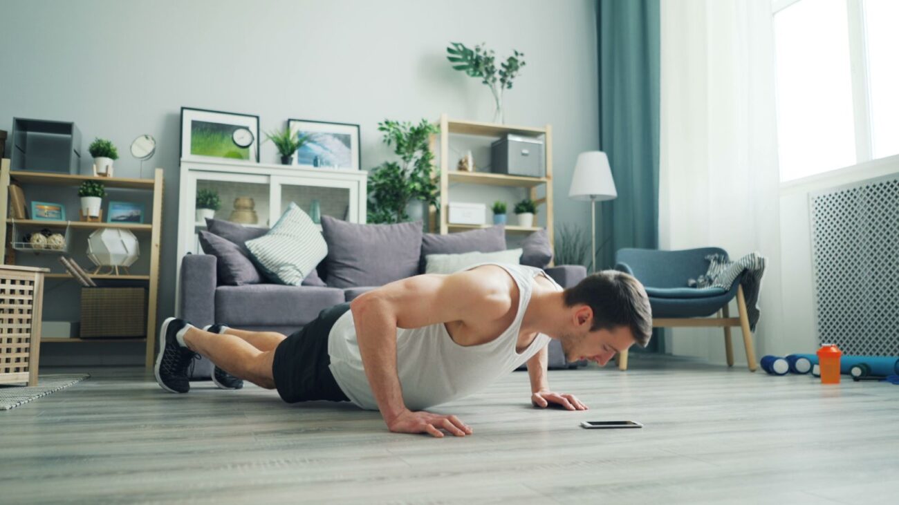 A man doing push-ups on the floor at home with no equipment, showing bodyweight training for building muscle