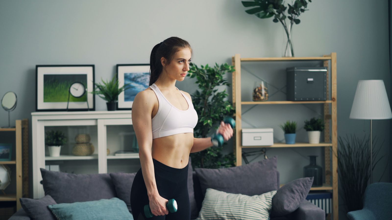 A person doing a dumbbell workout at home in a living room, showing that beginners can start training at home