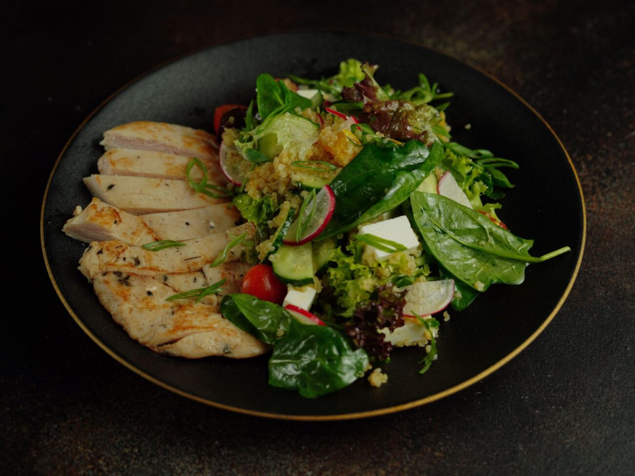 A balanced plate of grilled chicken and fresh salad, illustrating the sustainable, balanced eating behind a habits-based approach to fitness