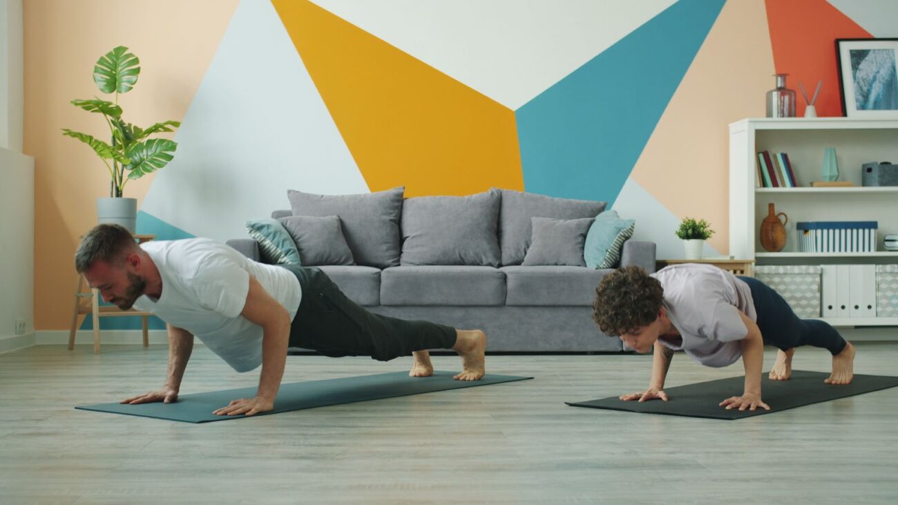 Two people doing push-ups on mats in a living room, showing that you can build strength at home without a gym