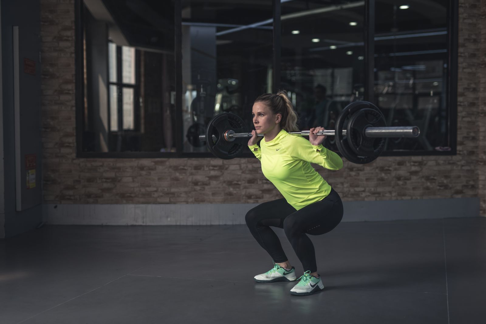 A lifter performing a barbell back squat in a gym, the main lift for building thigh size
