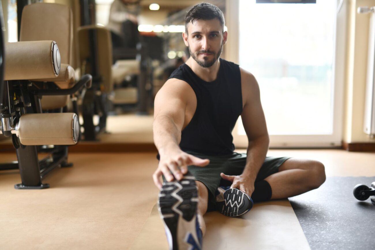 Lifter doing a seated hamstring stretch in the gym to keep mobility