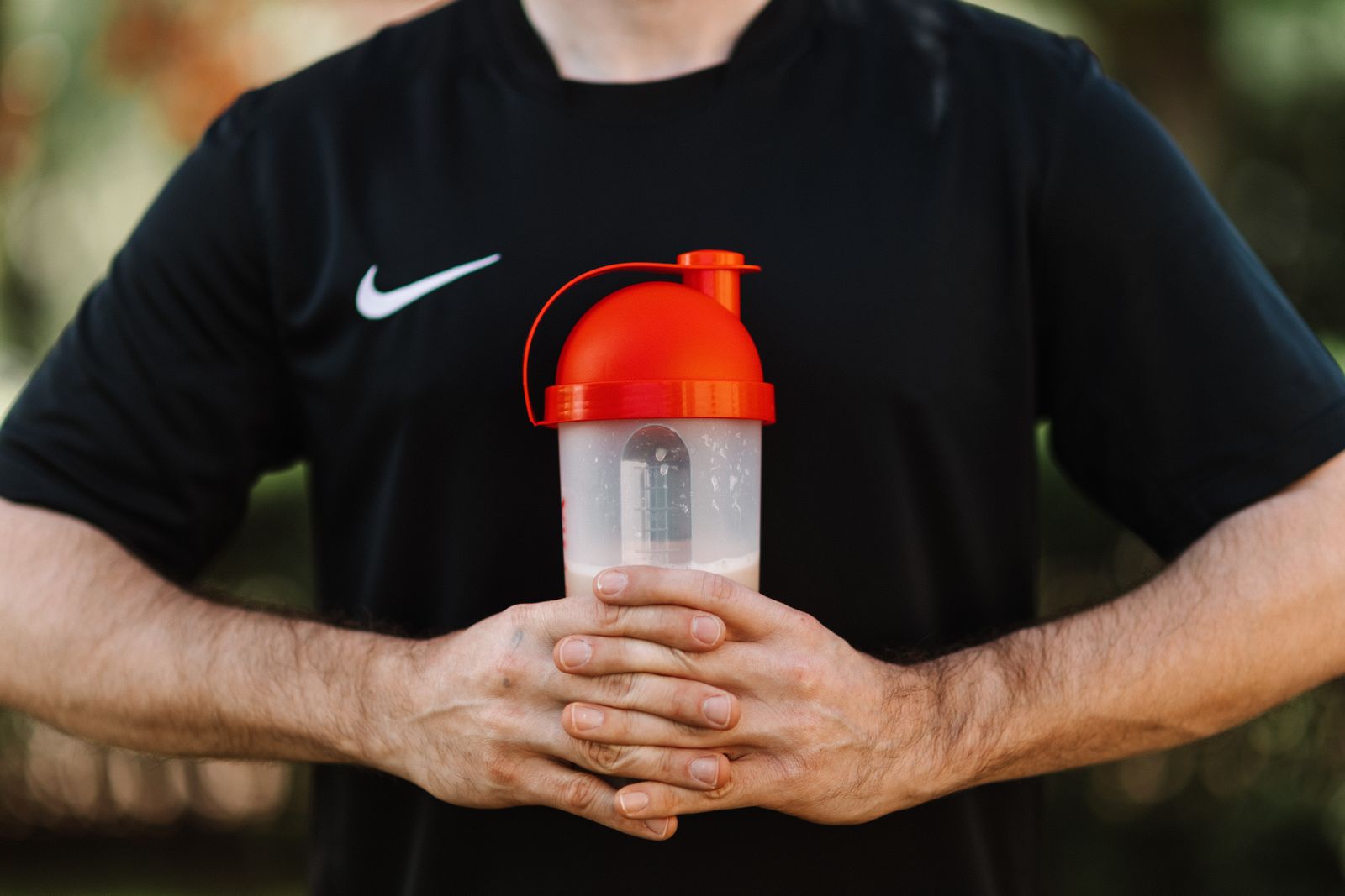 Person holding a protein shaker bottle after a workout