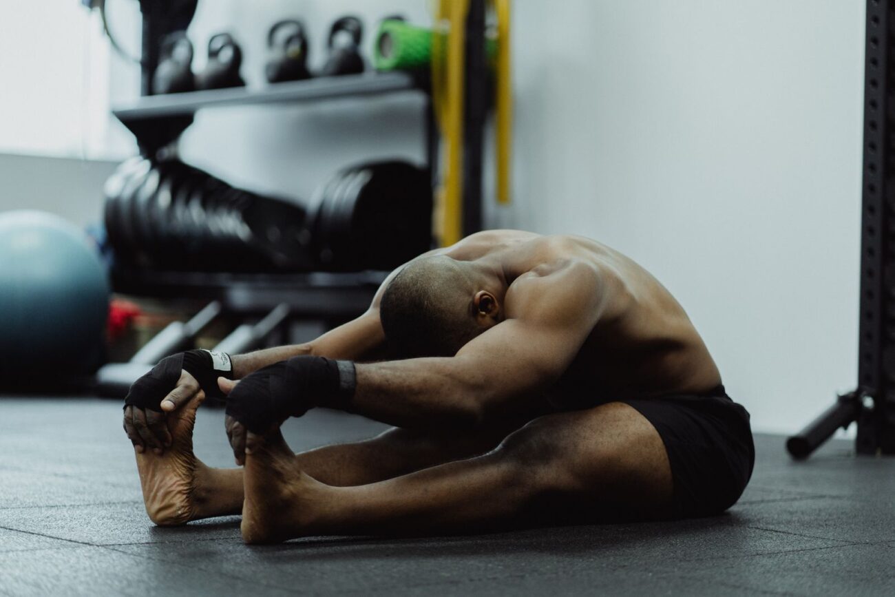 A person doing a seated flexibility stretch in a gym, illustrating the role of mobility in staying injury-free while lifting