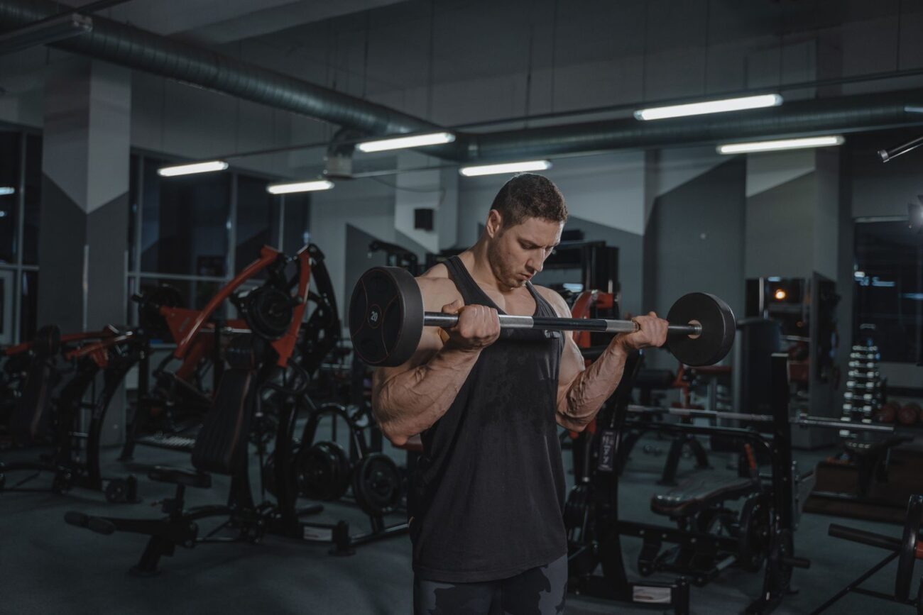 A lifter doing a barbell curl in a gym, illustrating a guide to natural bodybuilding myths and the reality behind them
