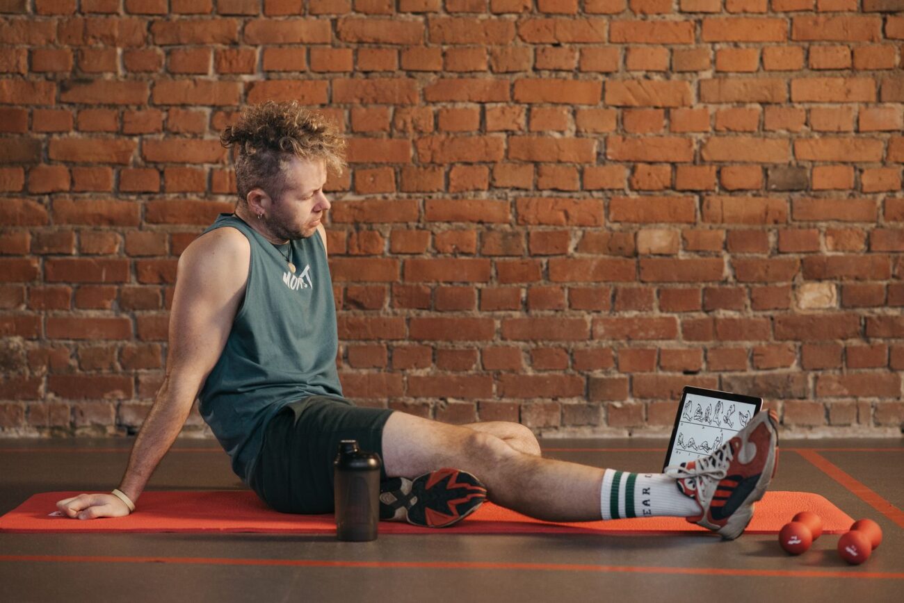 A person resting on a mat during a workout break, illustrating the recovery practices that support natural muscle building