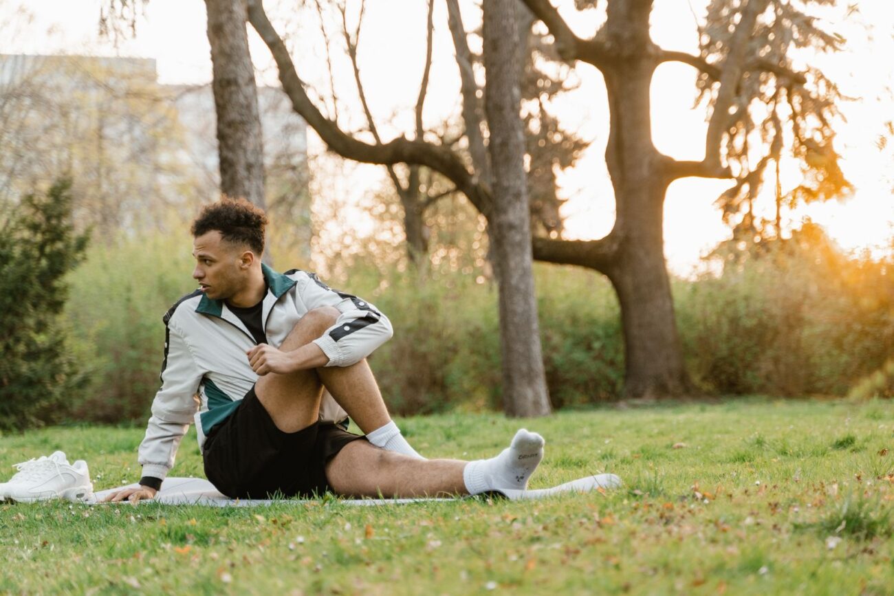Man doing a seated stretch outdoors to keep flexibility for lifting