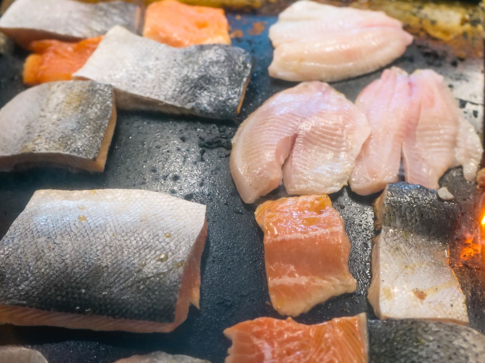 Pieces of fish cooking on a griddle, showing real protein sources that help keep you full while losing weight