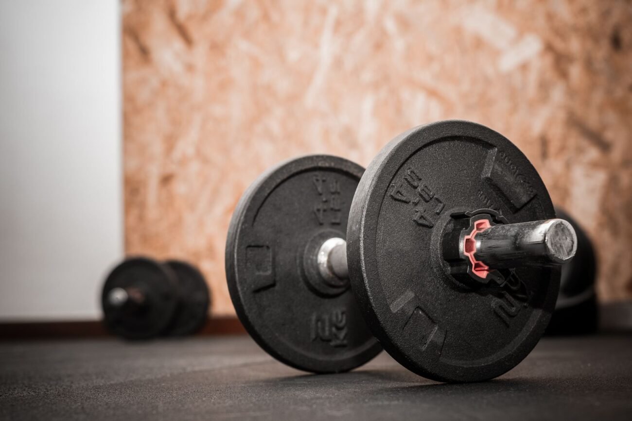 Close-up of a cast iron adjustable dumbbell with weight plates and a locking collar on a gym floor