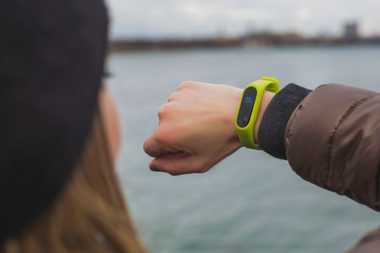 Person checking outdoor activity stats on a vibrant green fitness tracker band worn on the wrist