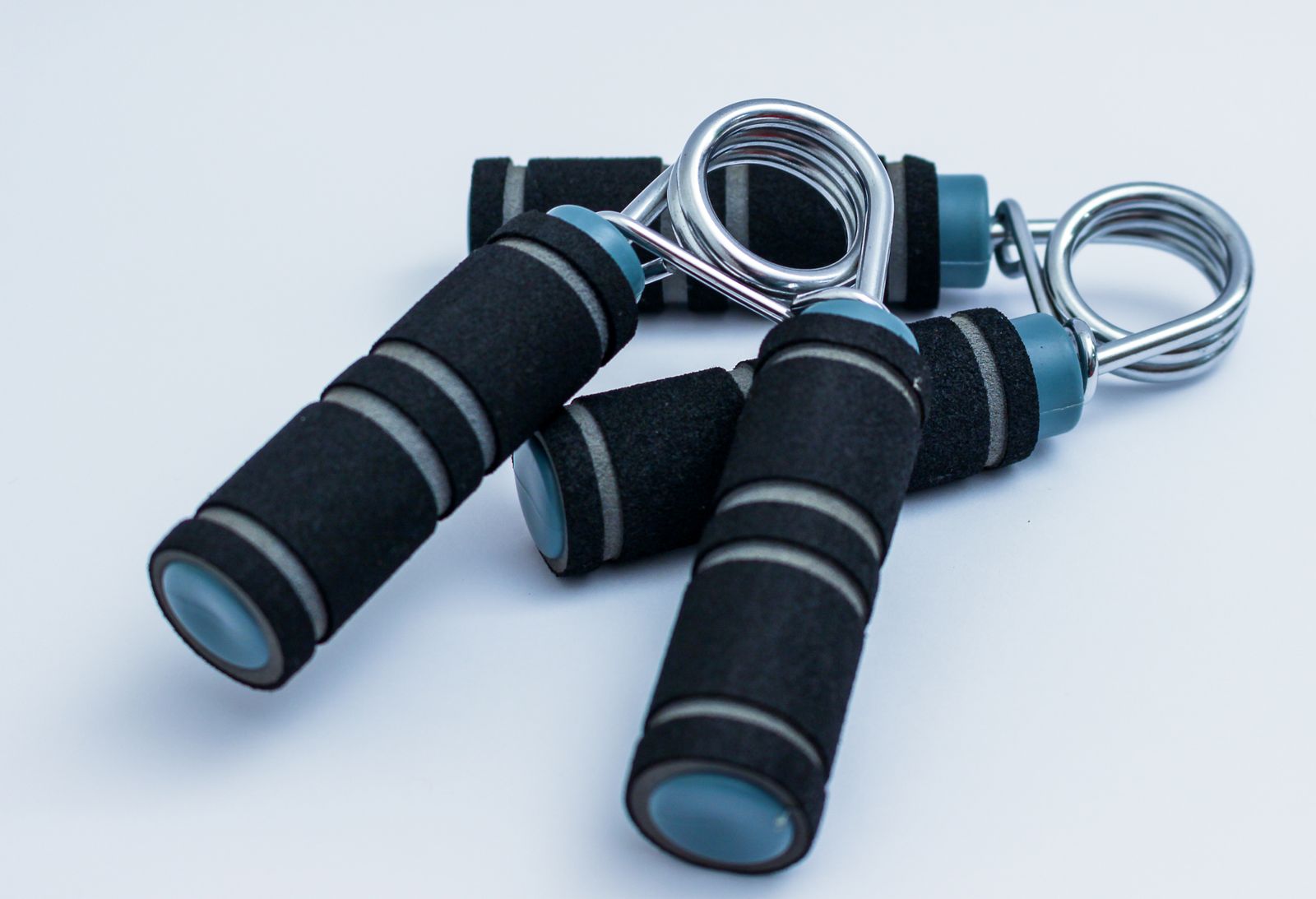 Pair of foam-padded hand strengtheners with steel springs resting on a white surface for grip exercise