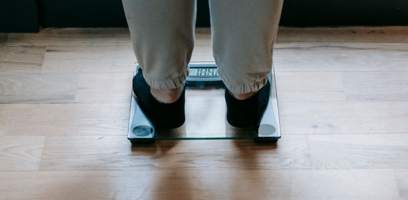 Low-angle view of a person standing on a glass digital bathroom body weight scale