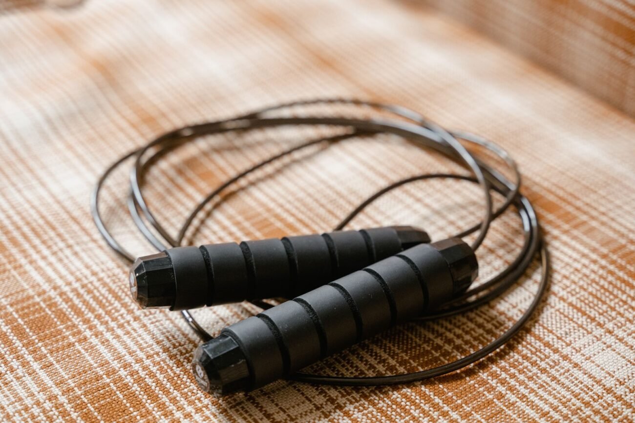 Coiled black speed jump rope with ridged foam grip handles resting on a textured surface