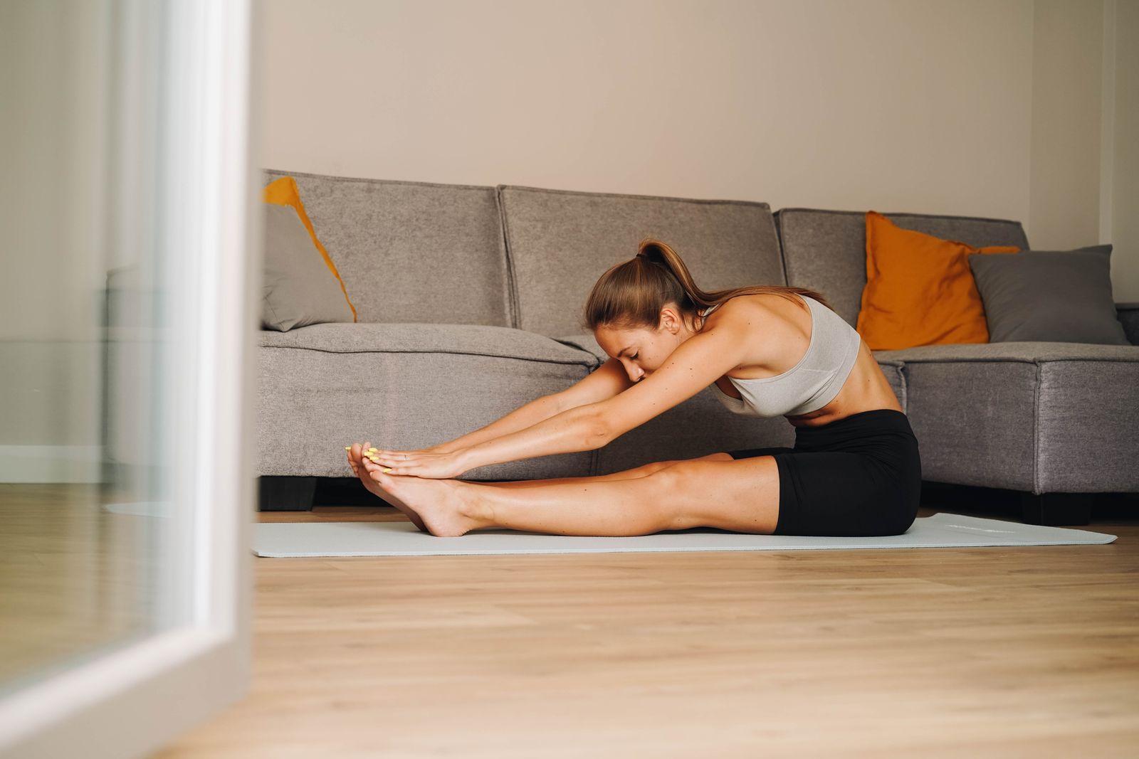 Person stretching their legs on a mat at home
