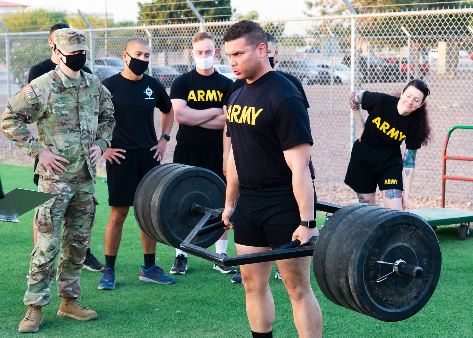 Athlete performing a heavy trap bar deadlift with bumper plates outdoors during a physical fitness assessment