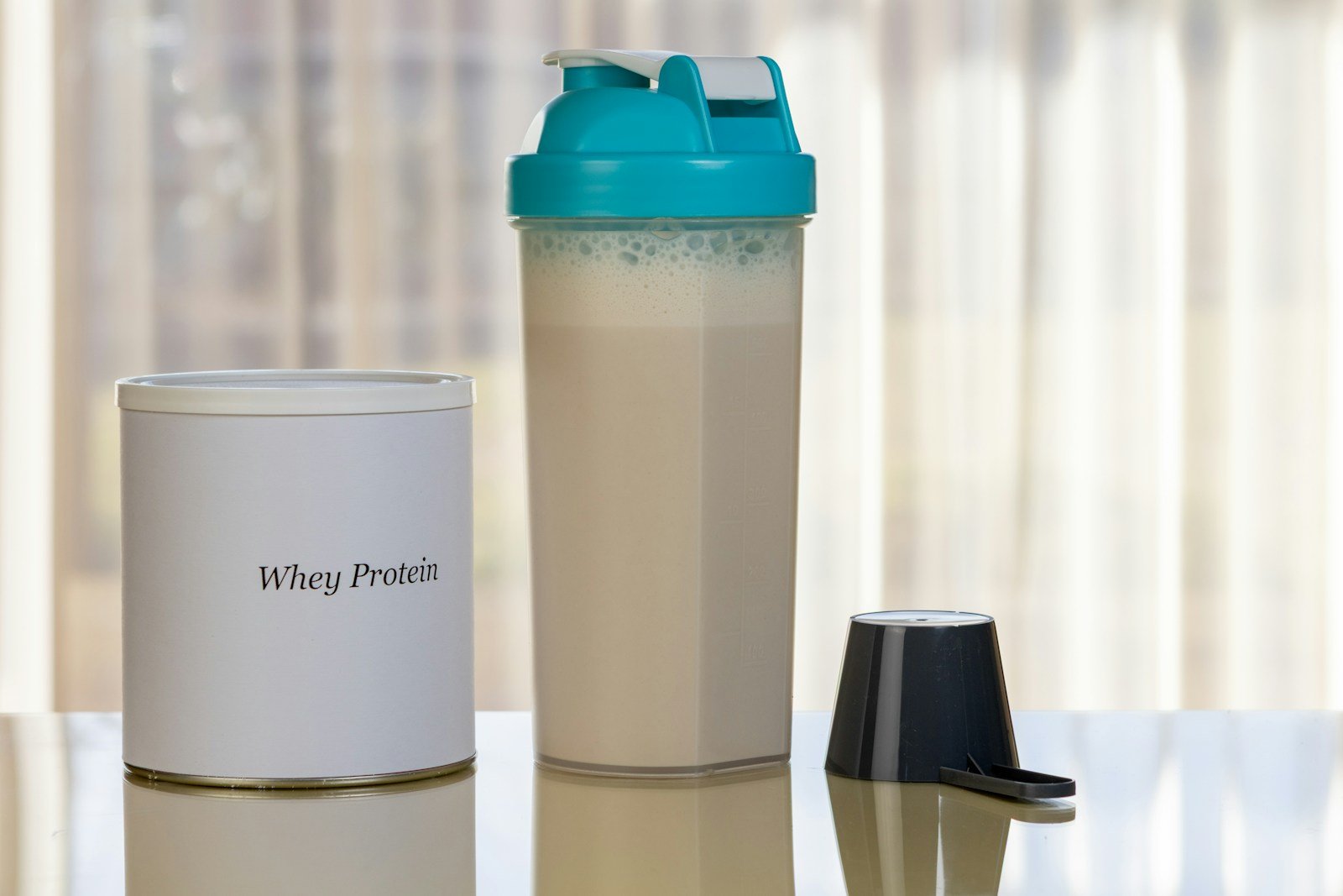 A protein shaker bottle with a shake beside an unbranded whey protein container